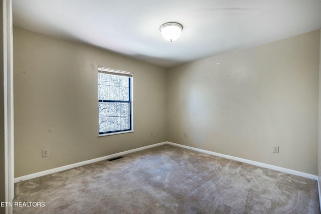 spare room featuring baseboards, visible vents, and carpet floors