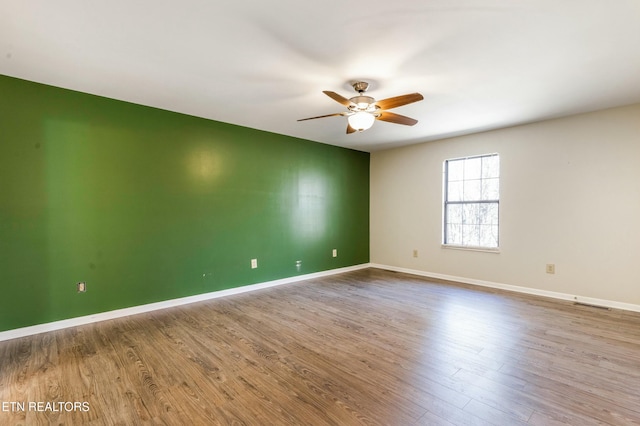 empty room featuring visible vents, baseboards, a ceiling fan, and wood finished floors