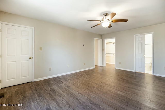 unfurnished bedroom featuring ceiling fan, ensuite bathroom, baseboards, and dark wood-style flooring