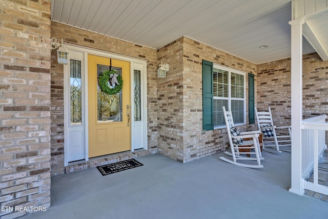 entrance to property with brick siding and a porch