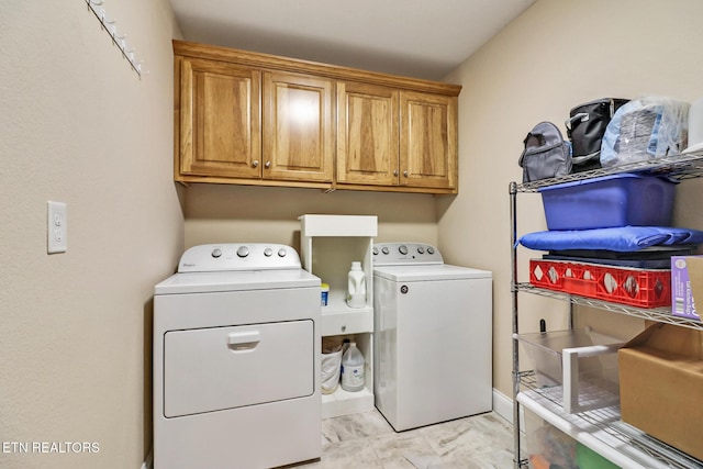 clothes washing area featuring washer and dryer and cabinet space