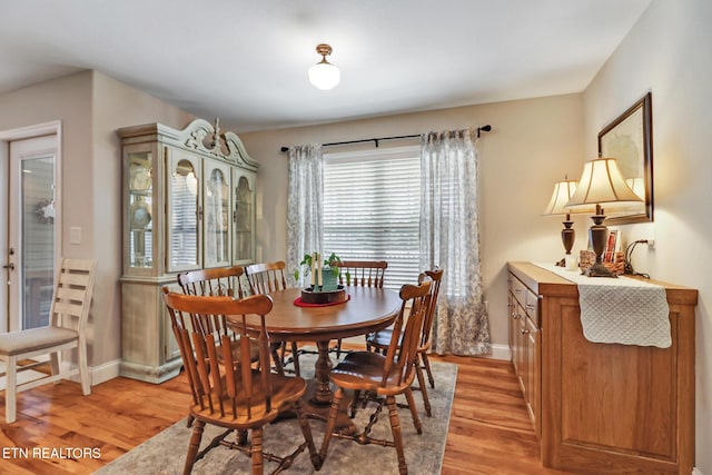 dining space with light wood-style flooring and baseboards