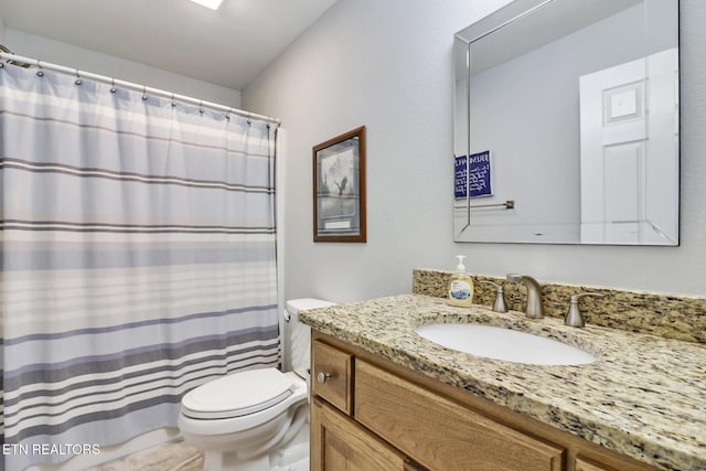 bathroom featuring toilet, vanity, and a shower with curtain