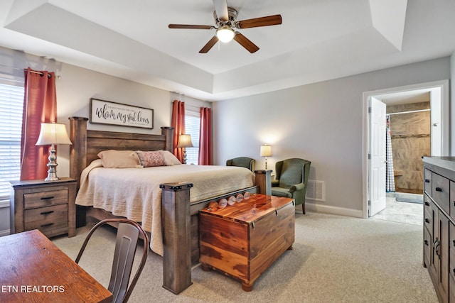 bedroom with visible vents, baseboards, a tray ceiling, light carpet, and a ceiling fan