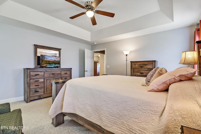 bedroom with light carpet, ceiling fan, a raised ceiling, and baseboards