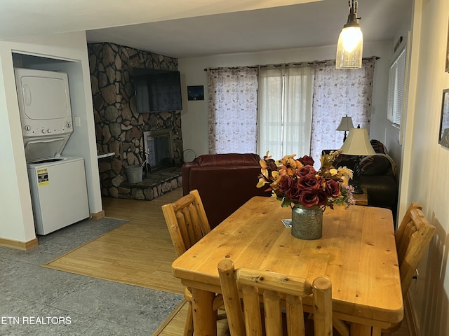 dining space with baseboards, stacked washer and dryer, and wood finished floors