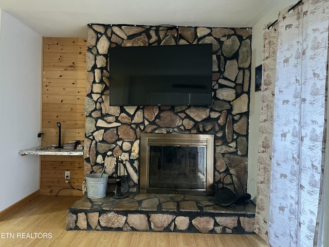 interior details featuring baseboards, a stone fireplace, and wood finished floors