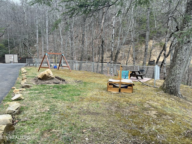 view of yard featuring a view of trees, fence, and a playground