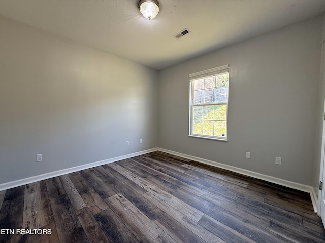 empty room with dark wood finished floors, baseboards, and visible vents