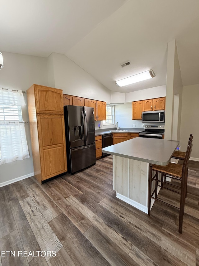 kitchen with dark wood finished floors, light countertops, vaulted ceiling, stainless steel appliances, and a sink