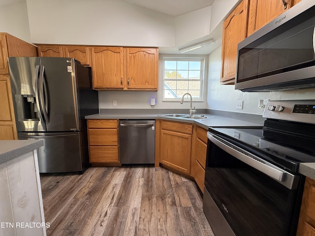 kitchen with dark wood finished floors, brown cabinets, stainless steel appliances, and a sink