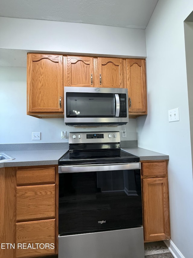 kitchen with baseboards, brown cabinets, and stainless steel appliances