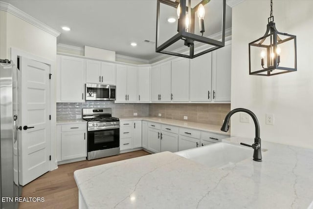 kitchen with tasteful backsplash, crown molding, appliances with stainless steel finishes, white cabinets, and a sink