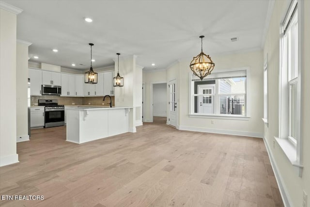 kitchen featuring ornamental molding, light countertops, appliances with stainless steel finishes, backsplash, and a chandelier