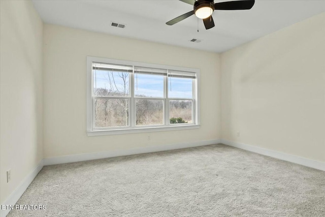 carpeted empty room with visible vents, a ceiling fan, and baseboards