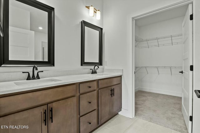 bathroom with double vanity, a spacious closet, baseboards, and a sink