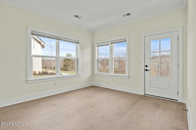 interior space featuring crown molding, light wood-style flooring, baseboards, and visible vents