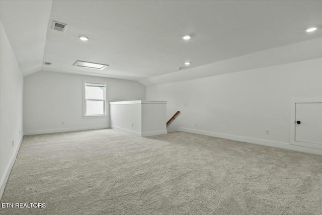 additional living space with lofted ceiling, light colored carpet, and visible vents