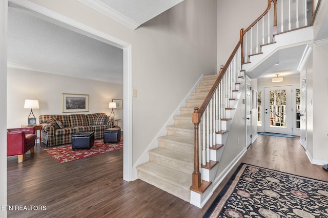 staircase featuring baseboards, a textured ceiling, wood finished floors, and ornamental molding