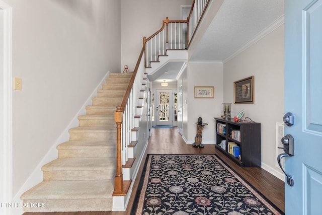 foyer featuring stairway, baseboards, wood finished floors, and ornamental molding