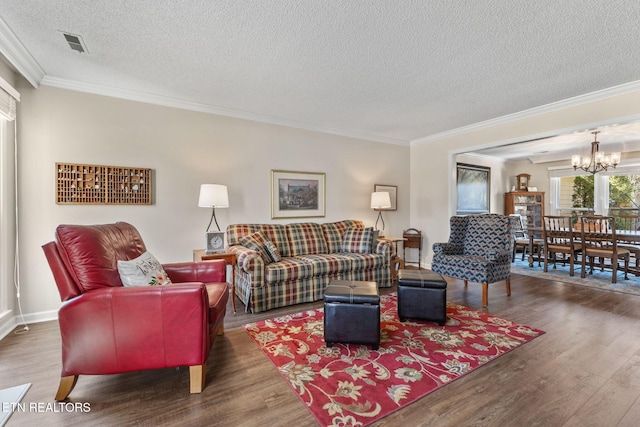 living room featuring visible vents, an inviting chandelier, wood finished floors, and ornamental molding