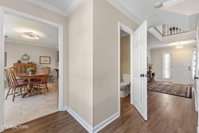 entryway with wood finished floors and crown molding