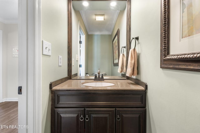 bathroom featuring baseboards, vanity, wood finished floors, and crown molding