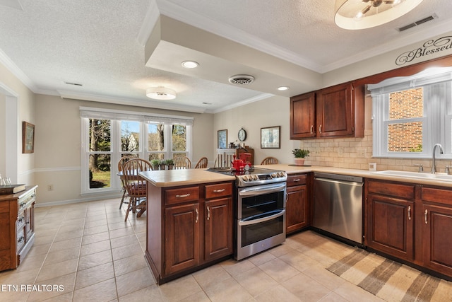 kitchen with visible vents, a peninsula, a sink, stainless steel appliances, and light countertops