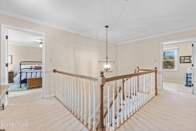 hallway with an upstairs landing, carpet flooring, and crown molding