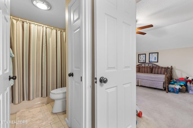 bathroom featuring tile patterned flooring, ceiling fan, toilet, shower / tub combo with curtain, and a textured ceiling