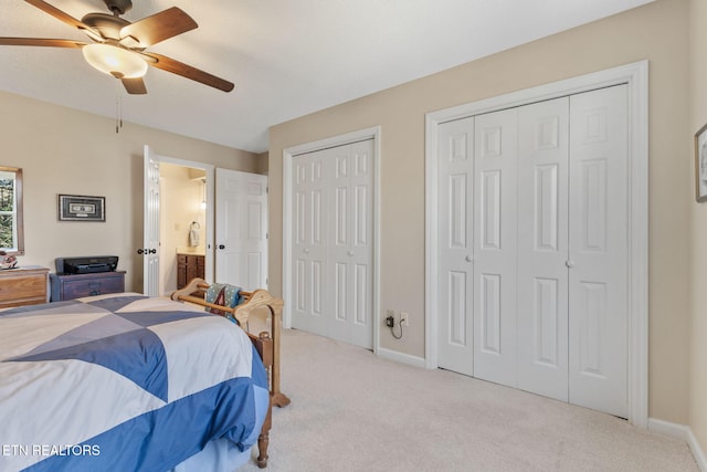 bedroom with carpet, baseboards, ensuite bath, ceiling fan, and multiple closets