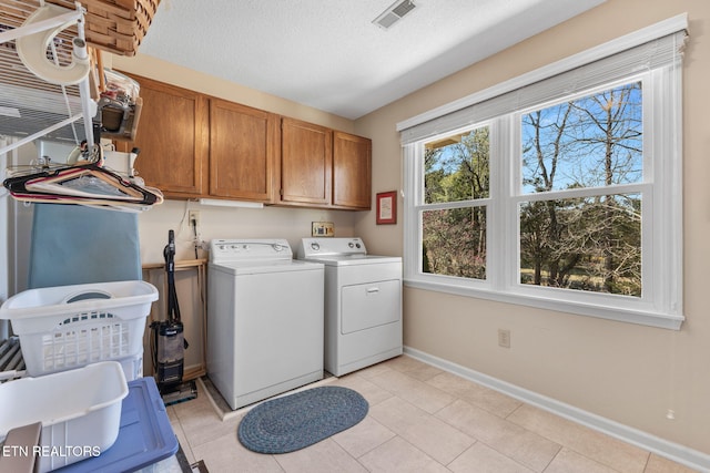 clothes washing area featuring baseboards, visible vents, cabinet space, a textured ceiling, and washer and clothes dryer