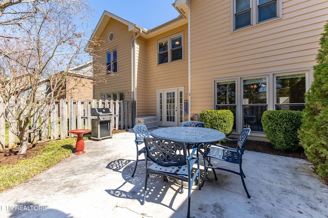 view of patio with outdoor dining space, area for grilling, fence, and french doors