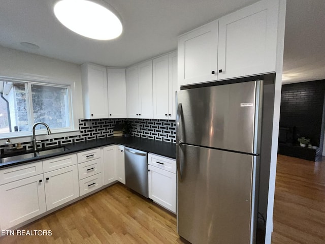 kitchen featuring dark countertops, appliances with stainless steel finishes, white cabinets, and light wood finished floors
