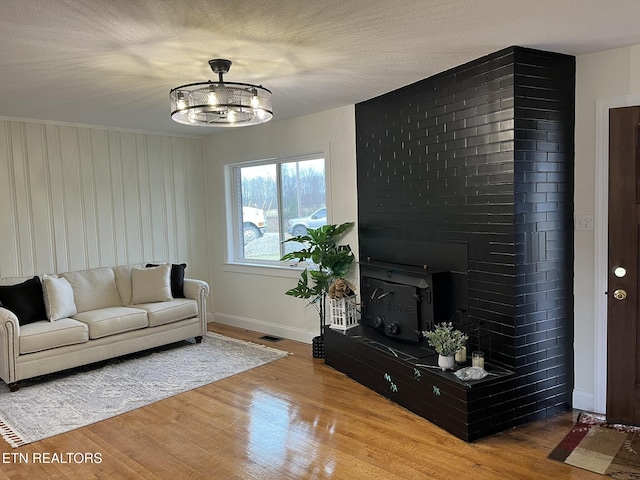 living area with visible vents, a textured ceiling, wood finished floors, a fireplace, and baseboards