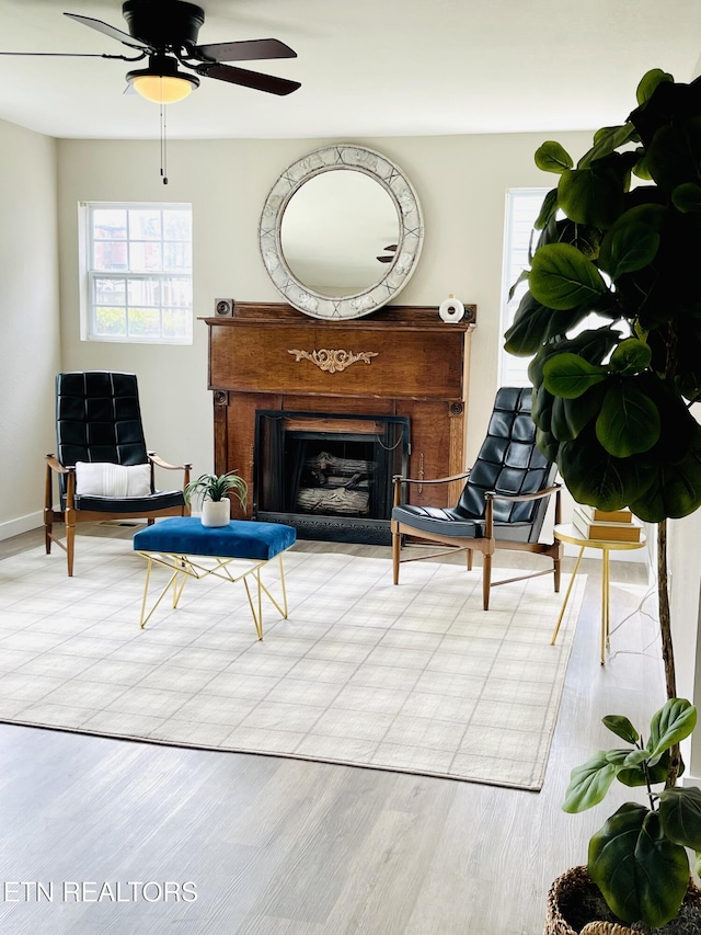 living room with baseboards, a fireplace, wood finished floors, and a ceiling fan