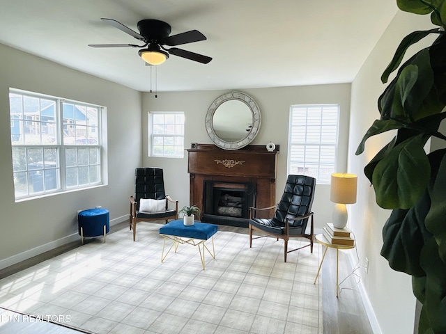 sitting room with a fireplace, a ceiling fan, and baseboards