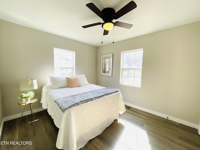 bedroom with multiple windows, baseboards, dark wood-style flooring, and ceiling fan