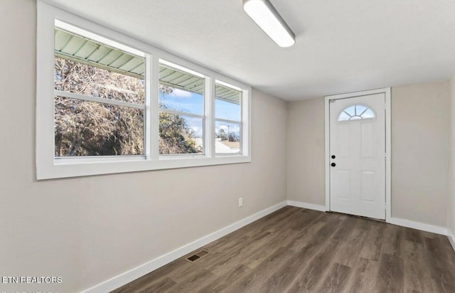 foyer with visible vents, baseboards, a textured ceiling, and dark wood finished floors
