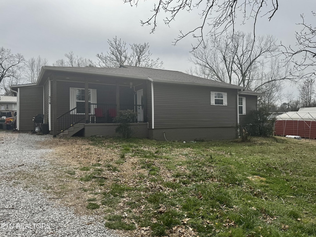 view of front of home featuring covered porch, driveway, and a front lawn