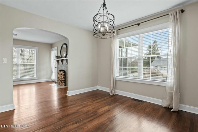 interior space with arched walkways, visible vents, a brick fireplace, and dark wood-style flooring