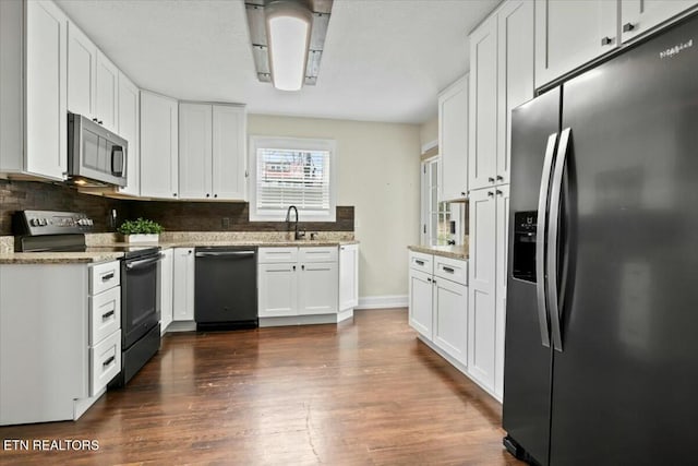 kitchen with dark wood-type flooring, decorative backsplash, appliances with stainless steel finishes, white cabinets, and a sink