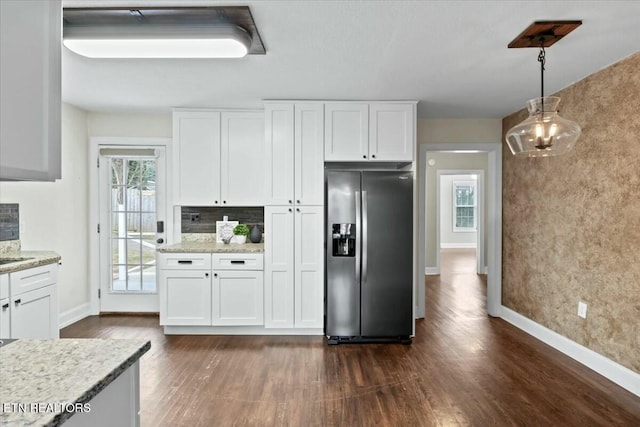 kitchen with dark wood-type flooring, backsplash, stainless steel fridge, white cabinets, and hanging light fixtures