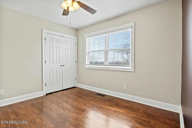 unfurnished bedroom with a closet, baseboards, visible vents, and wood finished floors