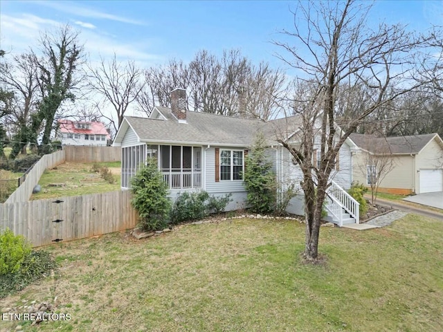 view of front of house with an outbuilding, a sunroom, a front yard, a shingled roof, and fence private yard