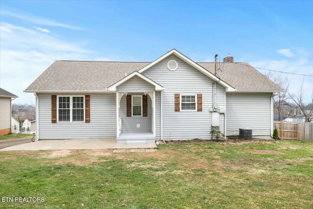 view of front of property featuring central air condition unit, fence, a front yard, a shingled roof, and a chimney