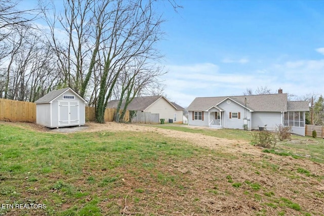 view of yard with an outbuilding, fence, a sunroom, and a shed