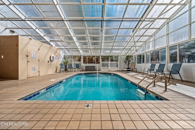 pool featuring glass enclosure, a patio, and fence