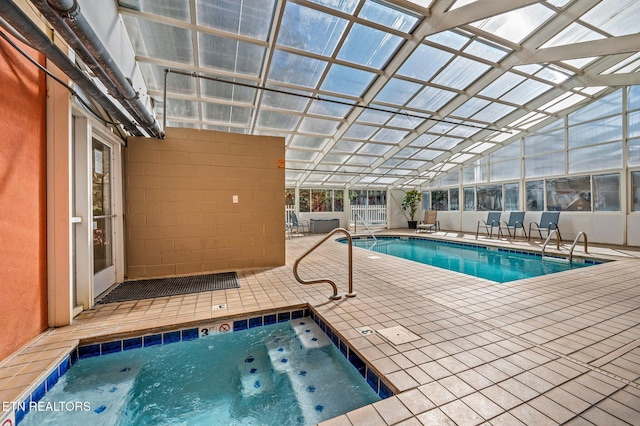 community pool featuring a patio area, glass enclosure, and an indoor hot tub