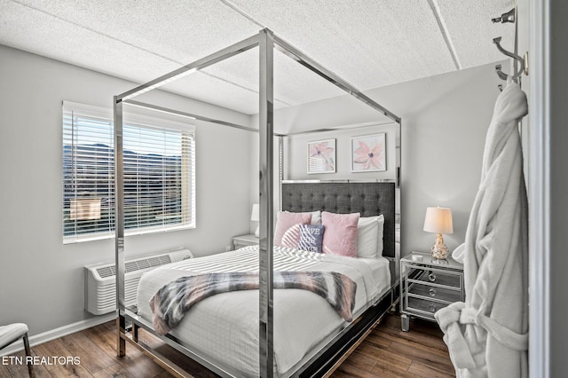 bedroom featuring wood finished floors, baseboards, and a wall mounted AC